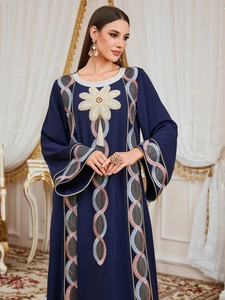 Détails du caftan bleu foncé montrant la broderie florale et les accents de glands métalliques