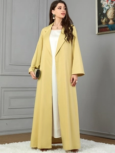 Detail of yellow long-sleeve lapel jacket paired with a white silk dress and fashion clutch