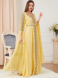 Detail of elegant yellow kaftan dress with golden lace embroidery and split cape sleeves
