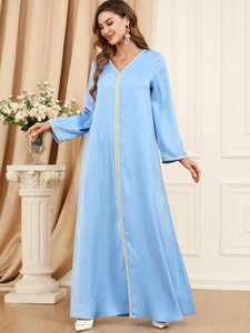 Detailed close-up of golden embroidery on a light blue satin kaftan with long sleeves