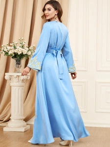 Detail of light blue satin dress featuring gold embroidery on sleeves and waist bow