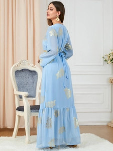 Detail von hellblauem Kleid mit goldenen Blattmustern und Rüschensaum in einer Innenaufnahme