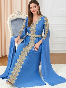 Close-up of golden embroidery on blue chiffon kaftan dress with long cape sleeves