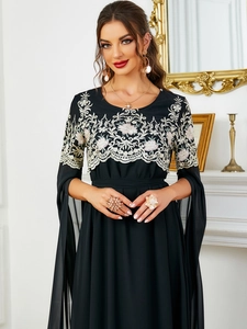 Détails de robe noire avec broderie florale et manches fendues de style cape