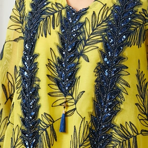 Détail de robe en mousseline jaune avec broderie de paillettes bleues et gland