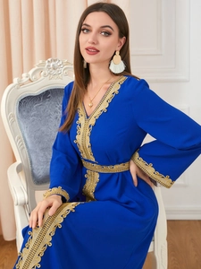 Detail of elegant royal blue kaftan dress with intricate gold embroidery on the neckline