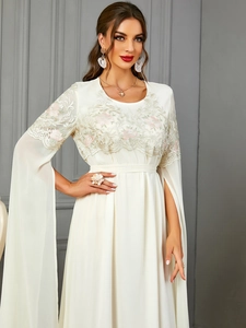 Broderies florales exquises et manches cape sur une élégante robe en mousseline blanche
