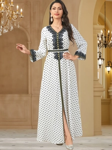 Detailed view of V-neckline with black lace trim and gold accents on a polka dot dress
