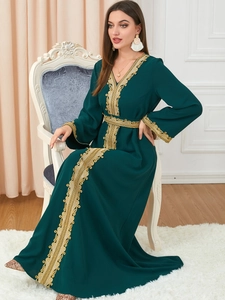 Detailed embroidery on a dark green kaftan dress with golden trim and V-neckline