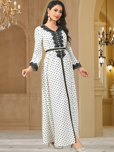Close-up of white polka dot dress featuring black lace trim and gold button detail