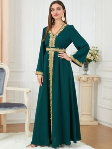 Detailed close-up of golden lace embroidery on elegant dark green long-sleeved dress