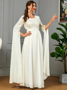 Détail de la robe en tulle blanc avec broderie florale et manches cape longues élégantes