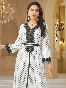 Detailed close-up of white polka dot dress with black lace trim and golden buttons