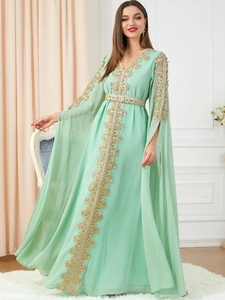 Detail of mint green kaftan dress with golden lace embroidery and metallic gold belt
