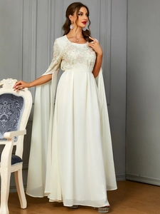 Détail de broderie florale sur robe longue crème avec manches cape fendues