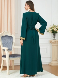Close-up of elegant dark green maxi dress featuring gold embroidery on the cuffs