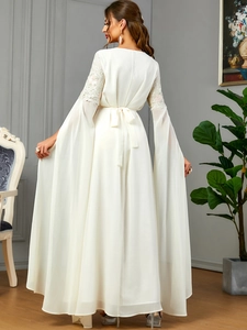 Détail d'une robe longue blanche avec broderie en dentelle et manches longues fendues