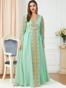 Detail of mint green kaftan dress featuring gold floral embroidery and jeweled waist belt