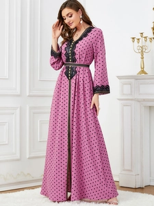 Detail of V-neck pink kaftan dress featuring black lace trim and golden button accents