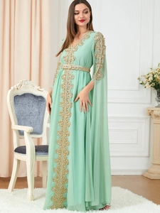 Detail of mint green kaftan dress with gold floral embroidery and split cape sleeves