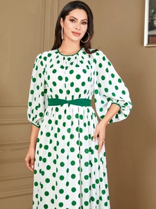 Detail of white dress with green polka dots, lantern sleeves and a matching waist belt