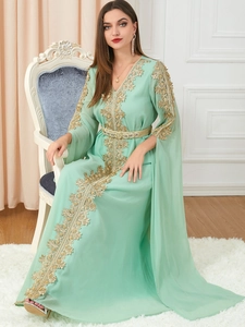 Detail of mint green kaftan dress featuring gold lace embroidery and beaded split sleeves