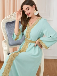 Detail of mint green kaftan dress featuring intricate gold embroidery and lace patterns
