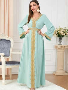 Detail of mint green Moroccan caftan dress featuring intricate gold embroidery and trim