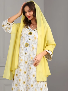 Detail of a lightweight yellow chiffon hijab paired with a white floral embroidered dress