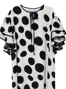 Close-up of white polka dot dress with triple-layered ruffle sleeves and black piping detail