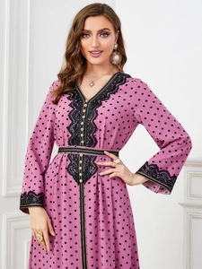 Detail of V-neckline with gold buttons and black lace trim on pink polka dot dress