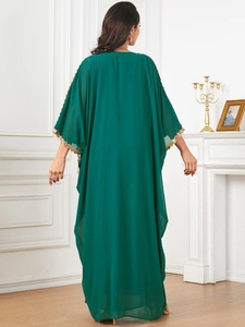 Detail of emerald green kaftan sleeve featuring intricate gold sequin lace trim embroidery