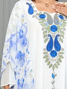 Close-up of elegant floral embroidery and paisley patterns on white kaftan dress