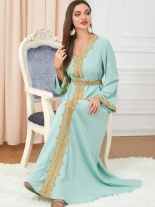 Detail of golden embroidery on mint green long-sleeved kaftan dress with elegant patterns