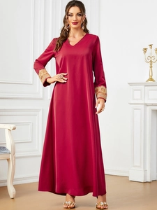 Detail shot of golden embroidery on sleeve of elegant red bohemian V-neck dress