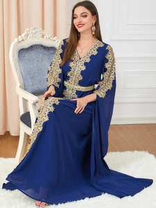 Close-up of golden floral embroidery on long sleeves and hem of the navy kaftan dress