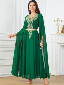 Detail of dark green maxi dress featuring gold leaf embroidery and cape-style slit sleeves