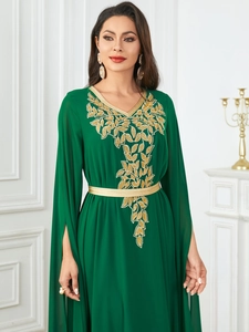 Detail of emerald green dress featuring gold leaf embroidery and split long sleeves