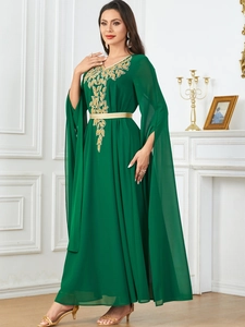 Detail of dark green gown showing golden leaf embroidery and elegant split cape sleeves