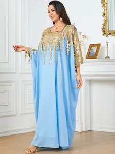 Detail of light blue kaftan with gold sequin embroidery and decorative tassels on the neckline