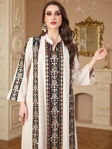 Detail of V-neck caftan dress featuring intricate black embroidery and gold sequins