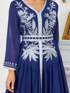 Close-up of elegant navy blue chiffon gown featuring intricate silver leaf embroidery