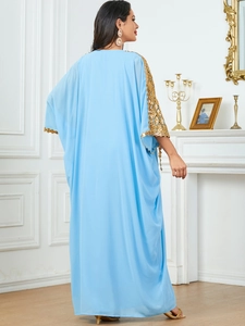 Detail of sky blue kaftan dress featuring gold geometric sequins and tassel sleeves