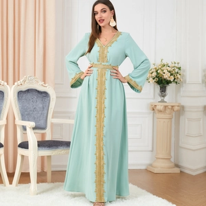 Elegant mint green kaftan dress with gold embroidery and long sleeves in luxury setting