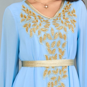 Detail of light blue kaftan dress featuring intricate gold sequin embroidery and a braided belt