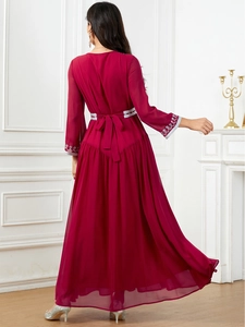 Detail of silver embroidery on waist and cuffs of an elegant deep red maxi dress