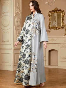 Detail of a contrast kaftan dress with green floral print and silver floral embroidery