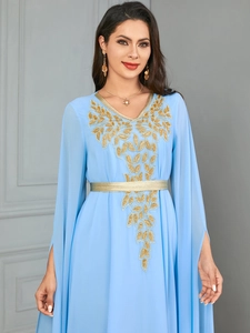 Detail of light blue kaftan dress with gold leaf embroidery and split sleeves