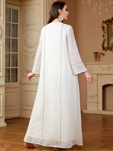 Détail de la broderie et texture sur robe longue blanche à manches longues avec motifs