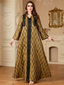 Detail of sequined embroidery and jacquard grid pattern on a golden V-neck Abaya